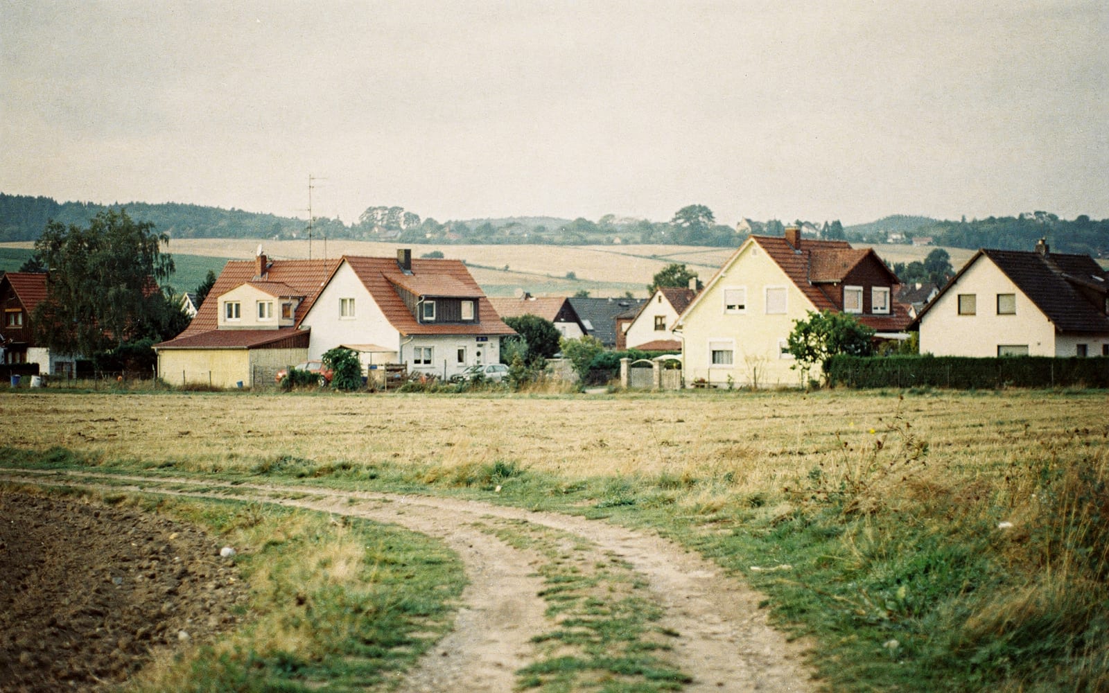 Ortsrand eines rheinhessischen Dorfes mit Feldweg und Einfamilienhäusern, Symbolbild zum Ratgeber über grundstück bewerten